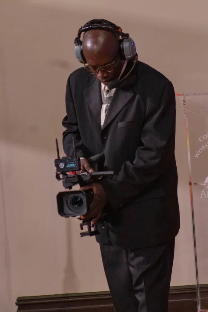 Black professional holding a camera.